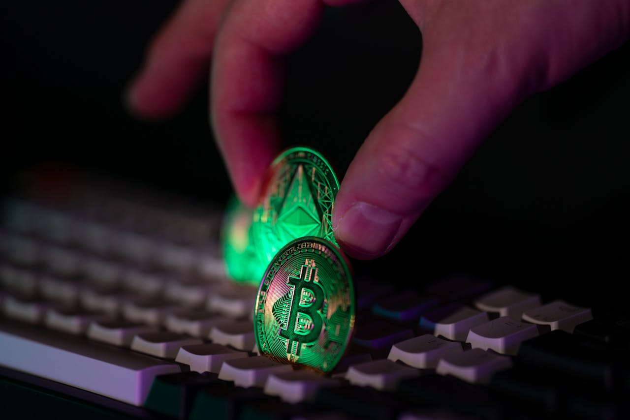 about-04 Close-up of a hand placing bitcoin and ethereum coins onto a computer keyboard, symbolizing cryptocurrency and digital finance.
